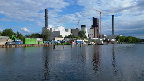 power plant undergoing conversion, retrofitting and renewal, featuring cooling towers, chimneys, and construction crane. smooth aerial view flight pull in drone