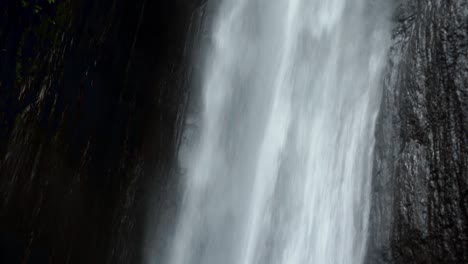 close-up, tilt-up detail shot of munduk waterfall, bali. showcases the power and beauty of the cascading water, highlighting the textures and details of the falls.