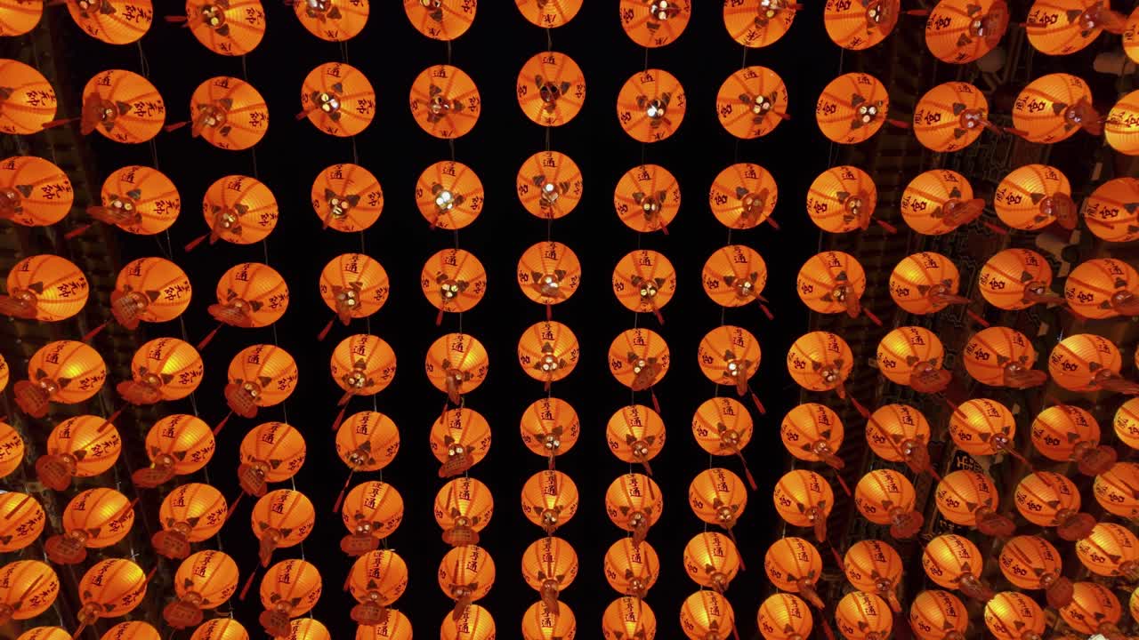 Festive red lanterns hanging in rows, seen from below with warm glowing light
