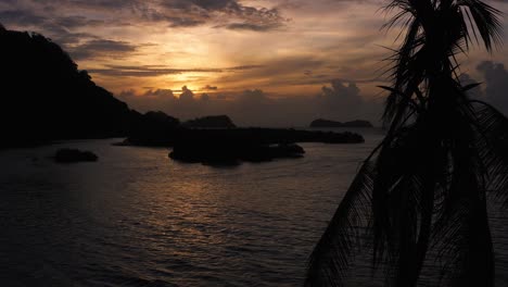 Colourful-orange-sunset-over-Panama-beach-Islands-silhouette-dolly-past-palm-tree