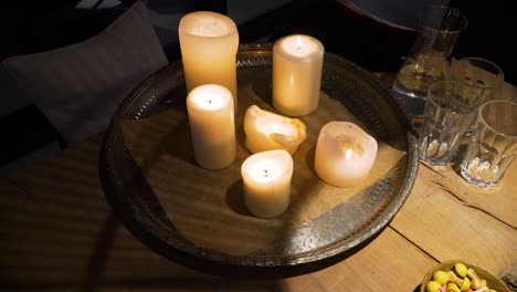 The-shot-of-light-candles-on-a-metal-tray-on-a-wooden-table-in-a-cozy-home-in-the-dark-evening