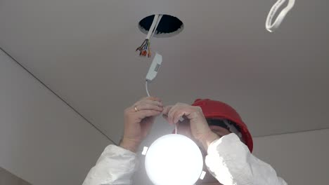 trabajador masculino profesional instala una luz led de ahorro de energía en el agujero del techo