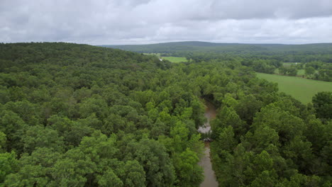 Pull-back-over-stream-and-woods-in-southern-Missouri-on-a-cloudy-summer-day