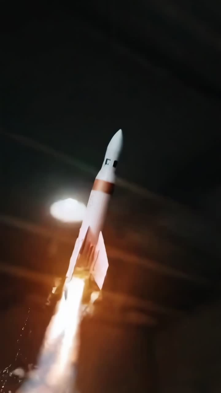 Side angle of a laptop displaying a futuristic rocket video, with a blurred background