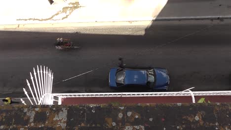 typical cuban city street with vintage cars, motorcycles and people passing by, birds-eye view from rooftop in matanzas