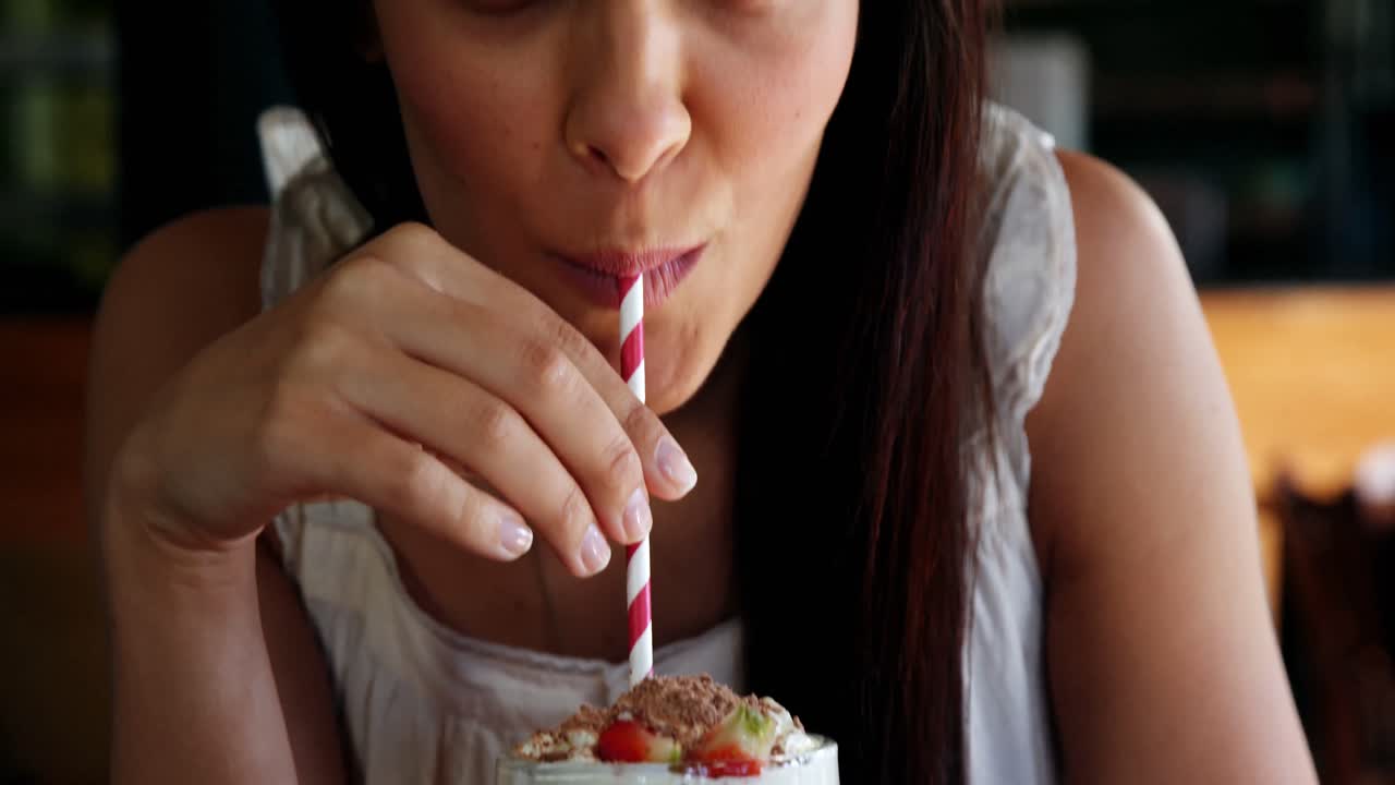 Beautiful woman drinking smoothie with straw