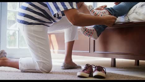 Grandmother-helping-granddaughter-to-wear-shoes-in-bedroom-4k