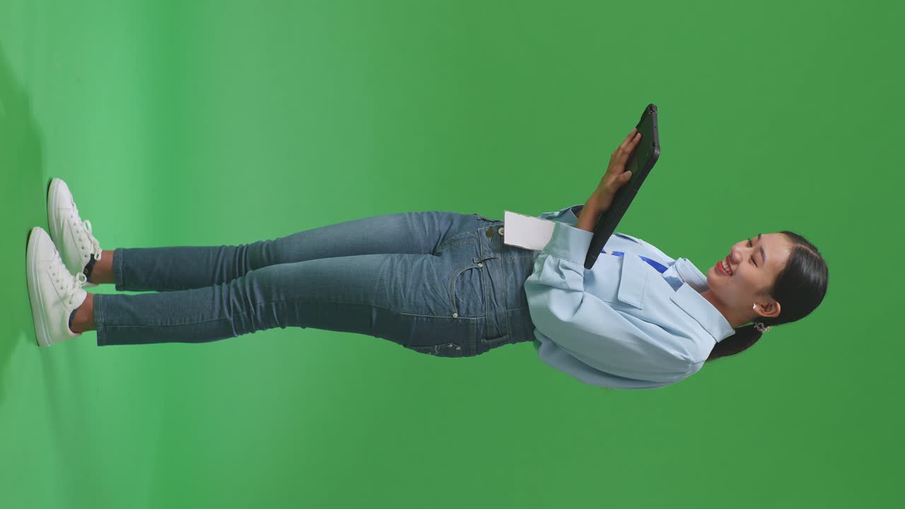 스튜디오에서 녹색 화면 배경에 태블릿을 사용하는 아시아 사업가 여성의 전체 몸의 측면 시각