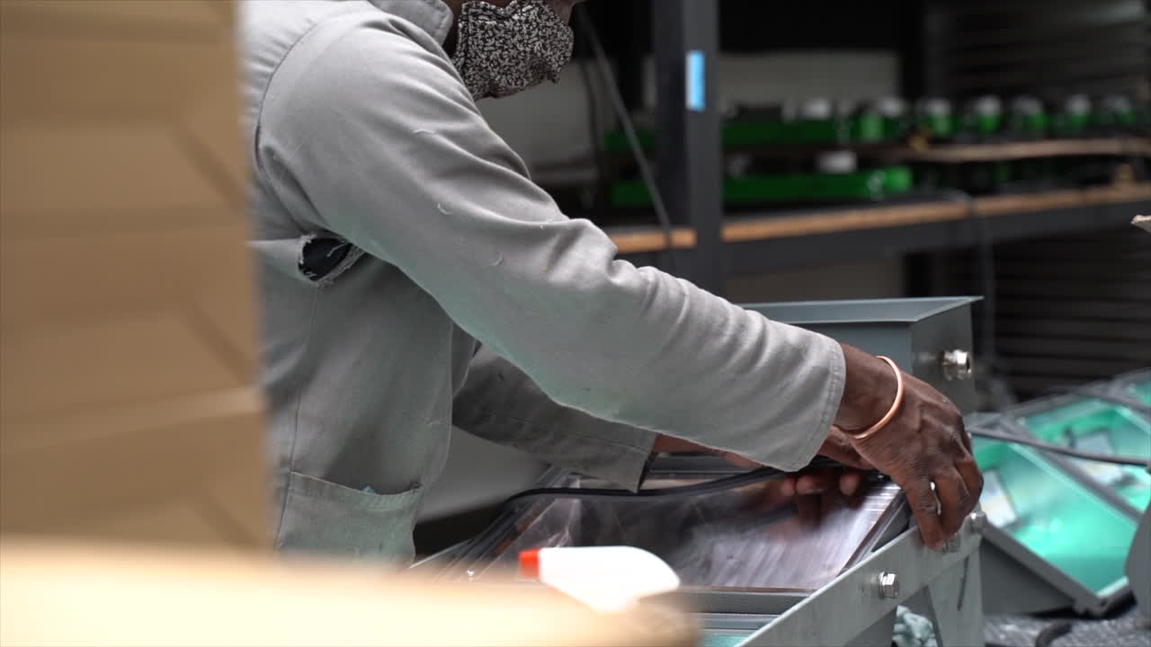 Black factory employee wearing a mask fixing waterproof seal to an LED light