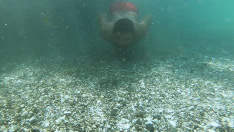 young man dive into cold water on bottom of river with shiny pebbles reflecting beautiful sunlight
