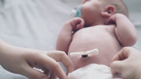 mother-hands-put-on-cute-newborn-baby-white-diaper