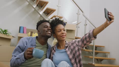 Video-of-happy-african-american-couple-taking-selfie-after-moving-into-new-house