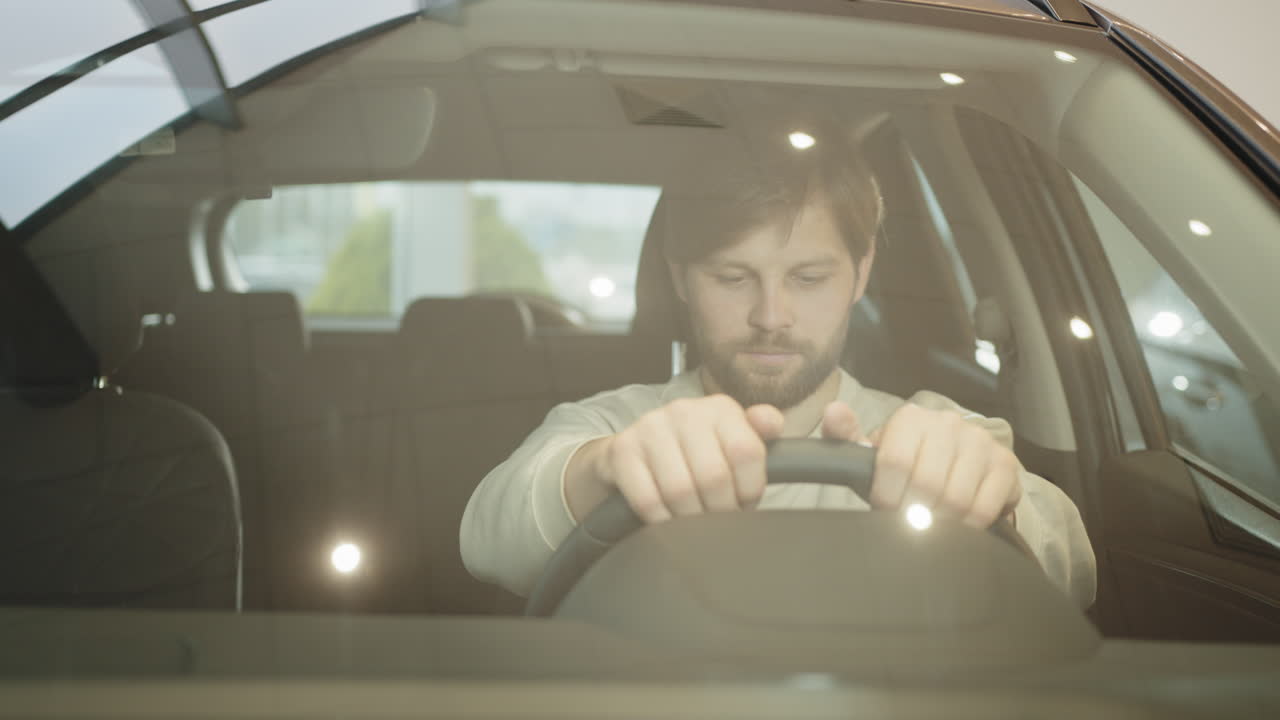 hombre feliz conduciendo un coche nuevo en una sala de exposiciones