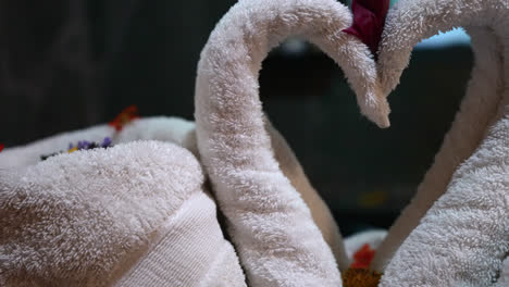 macro closeup of intricate towel swans folded and displayed with tropical flowers across back