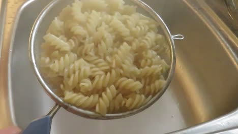 procedure of draining ready boiled pasta from a pot
