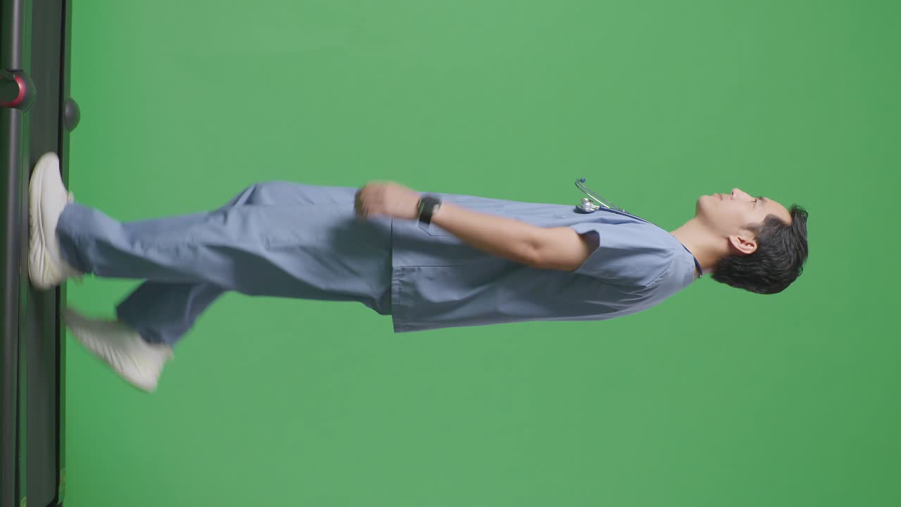 으로 볼 수 있는 전체 몸의 아시아 남성 의사는 스테토스코프를 가지고 병원에서 녹색 화면 배경에서 고 있습니다.