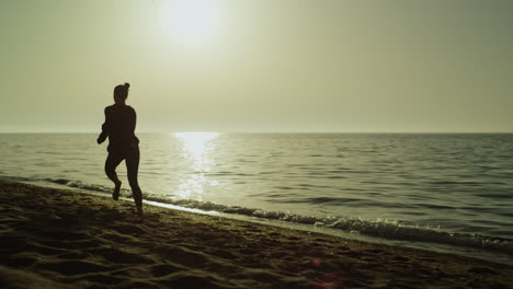 Mujer-Rápida-Corriendo-Sola-En-La-Playa-De-Arena-Al-Atardecer.-Silueta,-Niña,-Jogging,-Cerca,-Mar