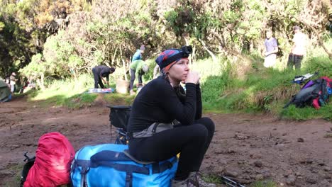 traveler with action cameras on her head sits on bags and waits for a team