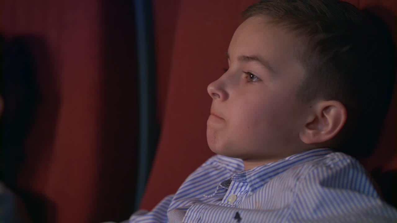 Gutt spiser popcorn på kino. Tenåring nyter kinomat