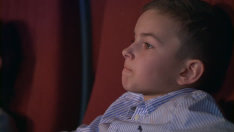 boy eating popcorn in cinema. teenager enjoy cinema food