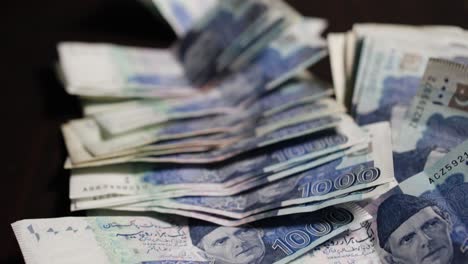 closeup panning shot of pakistani currency notes of 1000 rupee spreads on the surface