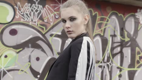 mujer elegante en un blazer negro contra una pared de graffiti