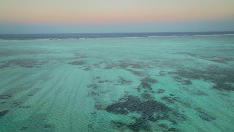 Mavic-3-Captura-La-Puesta-De-Sol-Sobre-Paje,-Zanzíbar,-Pintando-El-Cielo-Con-Nubes-Arremolinadas-Y-Volando-Sobre-El-Océano-Turquesa-Y-Los-Arrecifes-De-Coral.