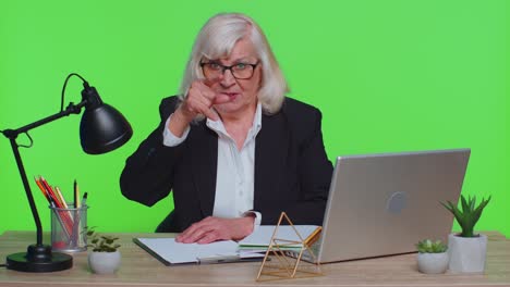 senior office businesswoman looking at camera doing phone gesture like says hey call me back contact