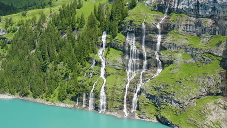 cinematic aerial of multiple waterfalls streaming from mountain into blue lake