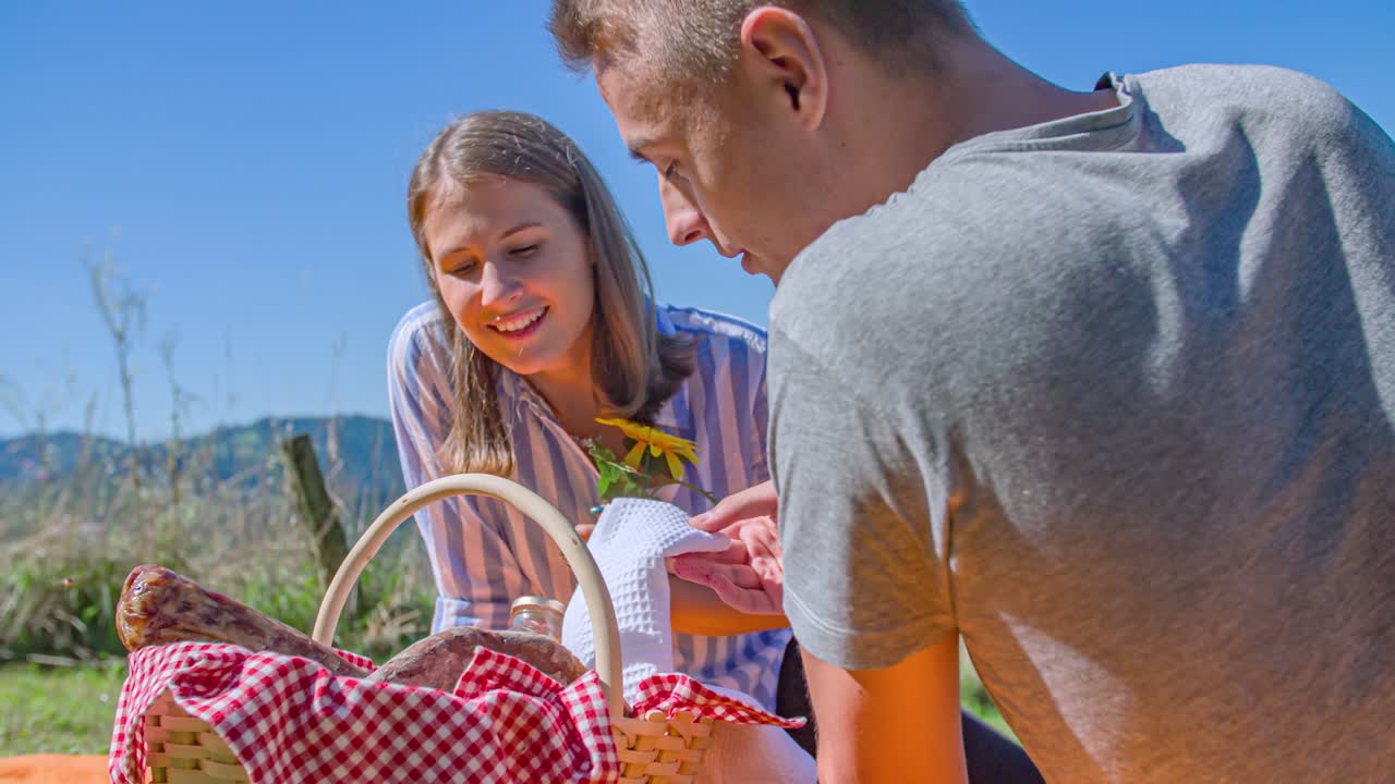 Boyfriend offering a romantic flower to his girl on a picnic