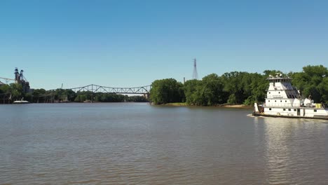 aerial view of a yacht sailing down a river towards a suspension bridge.