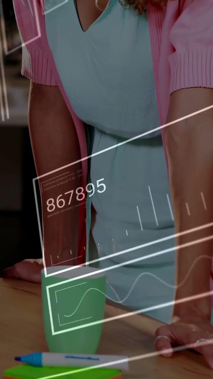 Vídeo vertical: Mulher apoiada na mesa, com um HUD tecnológico sobrepondo suas mãos e marcadores enquanto trabalha.
