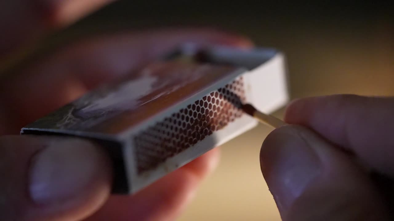 Hand Holding Match Stick Being Lit On Blurry Background. Rack Focus