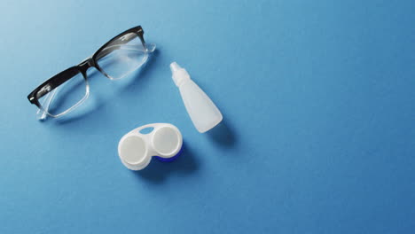 vídeo de un par de gafas, una caja de lentes de contacto y una solución sobre fondo azul con espacio para copiar