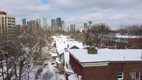 snow-covered residential roofs with city skyline background in greater toronto area, ontario, canada. aerial drone shot