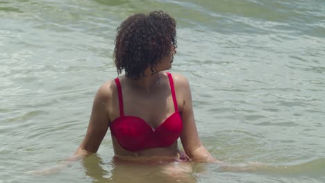 a sexy bikini-clad latina with curly hair embraces the beauty of a tropical beach setting