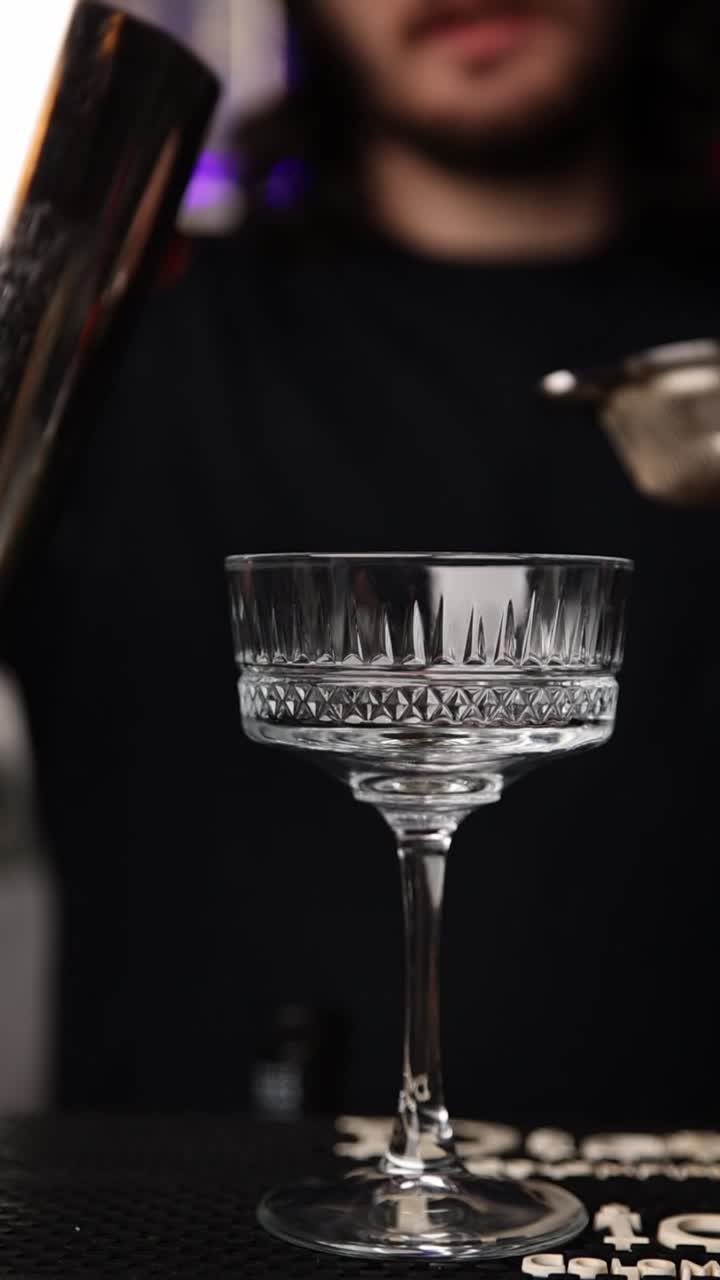 Cocktail versato attraverso il colino nel bicchiere