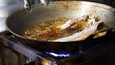 pork chop frying in a pan over flames