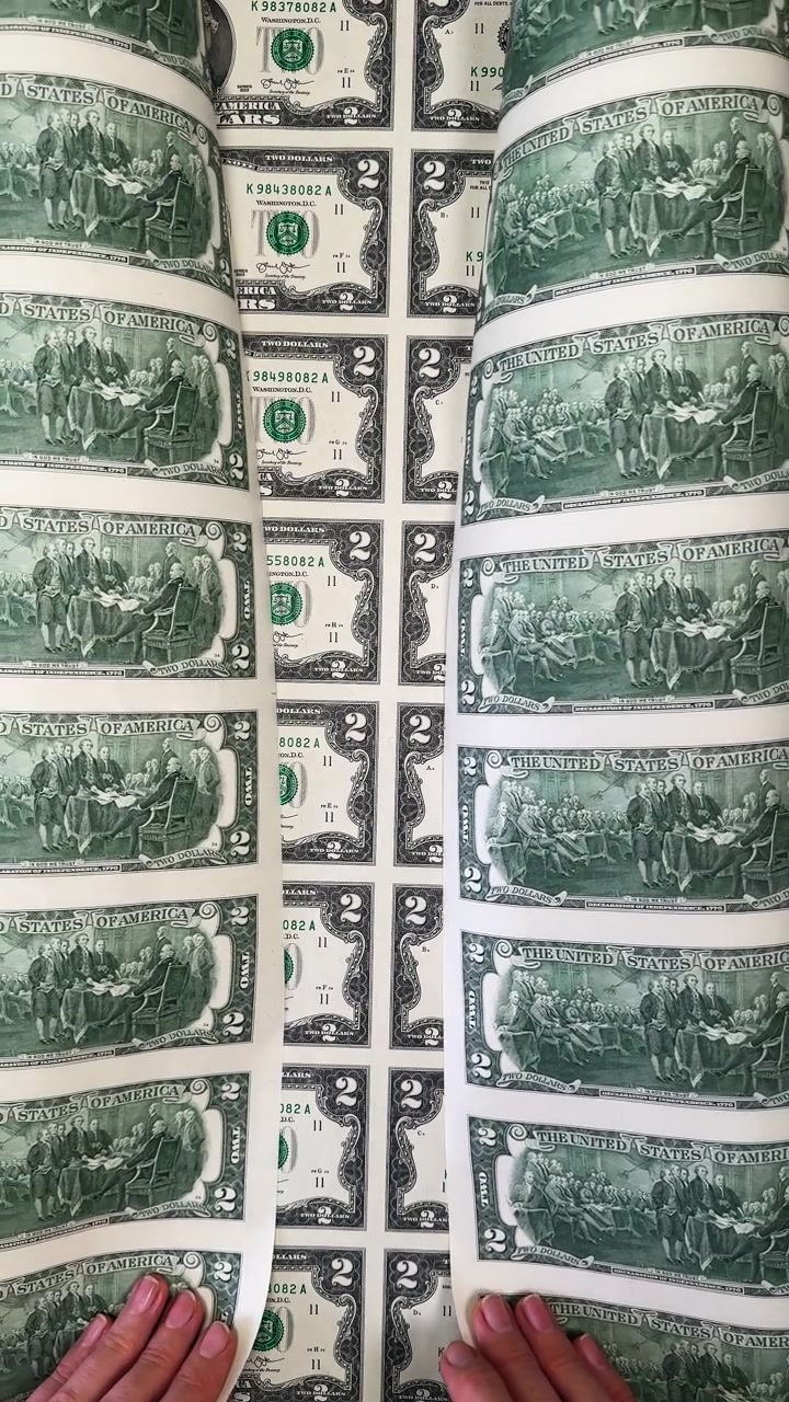 Onda astratta di banconote da due dollari non tagliate. Retro della valuta statunitense. Visione artistica di un foglio non tagliato di banconote da due dollari arrotolato per formare un motivo a onda.