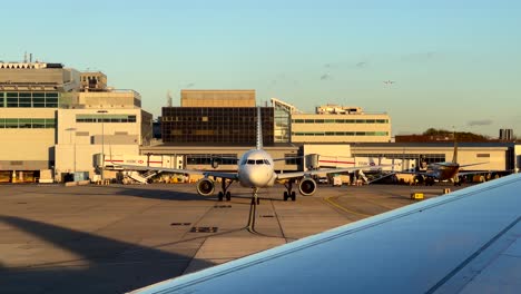 cinematic shot plane static on tarmac at large airport at sunset