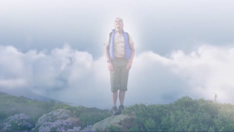 caucasian senior man hiking in countryside outstretching arms, over fast moving clouds