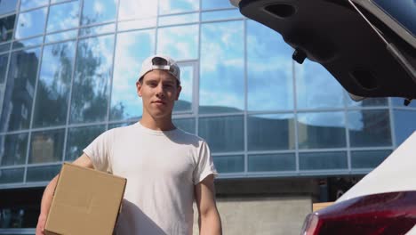 moving and delivery of manufactured goods. an employee holds a box in his hands and stands next to a car filled with parcels