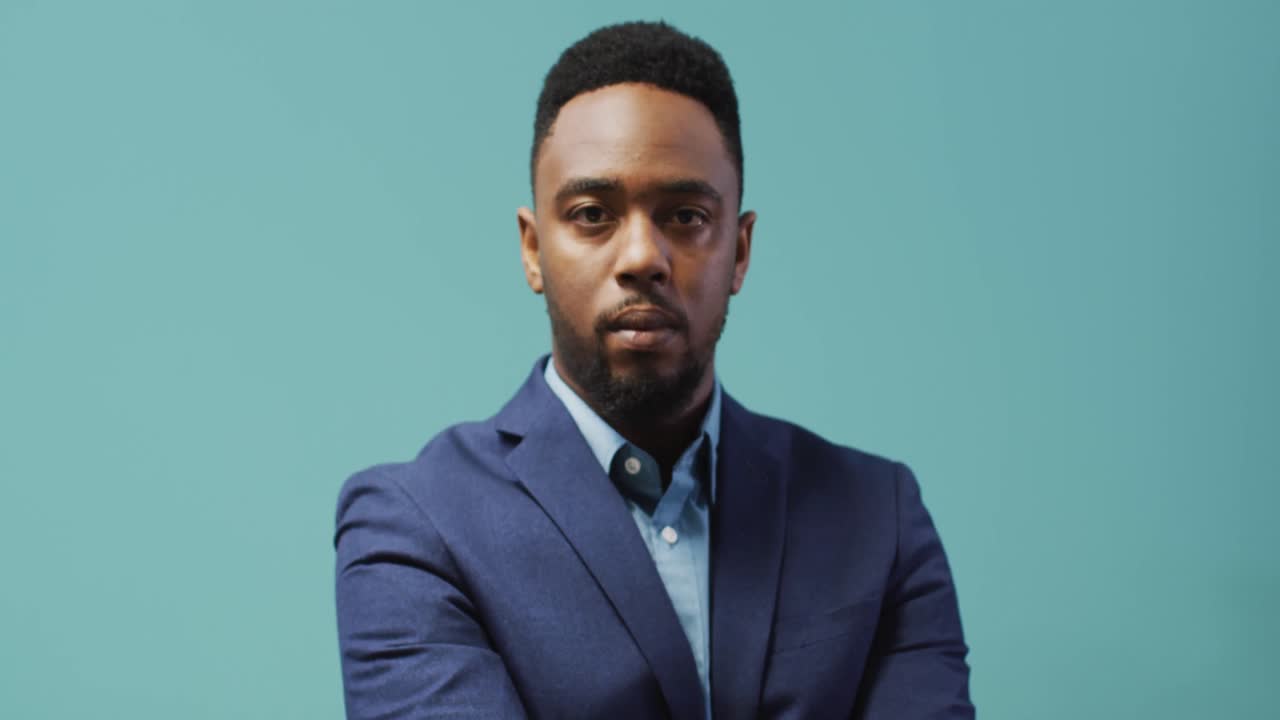 Video of smiling african american man looking at camera on blue background