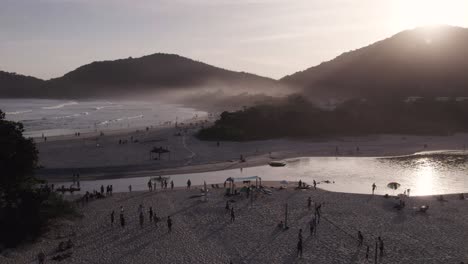 Drone-Moviéndose-Hacia-Atrás-En-Una-Hermosa-Playa-Con-Mucha-Acción-De-Personas-En-La-Arena