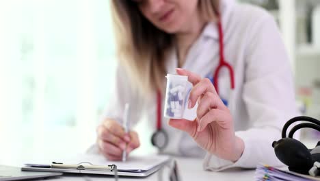 doctor holding a bottle of pills and writing a prescription