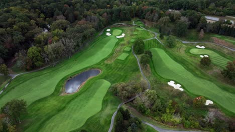 a high angle, aerial view over a well maintained golf course in westchester, new york during a cloudy day