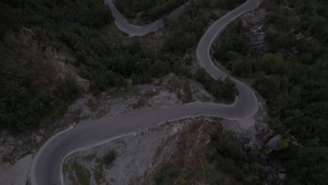 drone video of "revealing front shot ending front shot", about two motorcycles and some cars on the sh21 of the theth mountain pass in albania, the valbona valley in view of mount korab