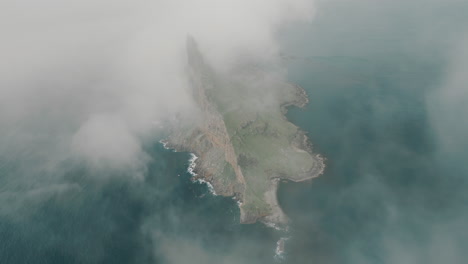 Dramatic Sea Stack and Cliffs Emerging from Mist in the Ocean