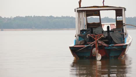 Plano-Medio-De-Un-Pequeño-Barco-De-Pesca-Asiático-Abandonado-Flotando-Cerca-De-La-Orilla