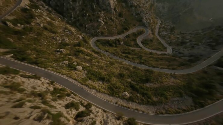 Ripresa da drone FPV che sorvola la strada a serpentina lungo il pendio di una catena montuosa rocciosa a Sa Calobra, Maiorca, Spagna, di giorno.